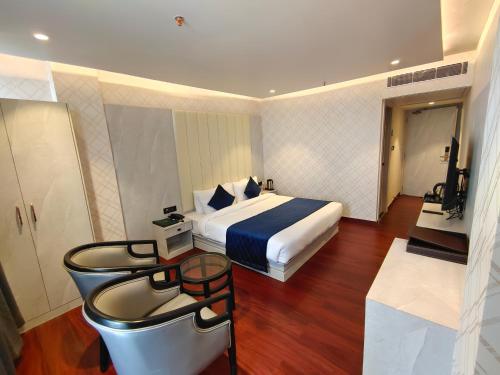 穆扎夫法尔普尔The Emerald Hotel & Siya Milan Banquets的酒店客房,配有一张床和一张桌子及凳子