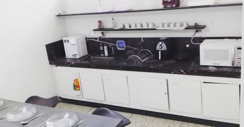 乌贝兰迪亚UDIHOSTEL HOSPEDAGEN的厨房配有白色橱柜和黑色台面