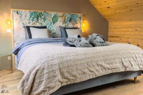 西内Le Clos du Rempart Suite & Jacuzzi的卧室配有一张带毯子和枕头的大床