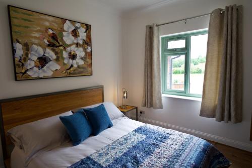 WiggintonTring Grange Cottage的一间卧室配有一张带蓝色枕头的床和一扇窗户。