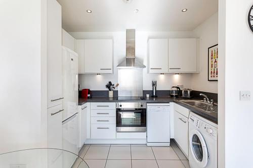 伦敦City-Close 1-Bed Apartment near Tower Hill的厨房配有白色橱柜、洗衣机和烘干机