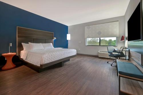 穆尔斯维尔Tru By Hilton Mooresville的一间卧室配有一张床、一张桌子和一把椅子