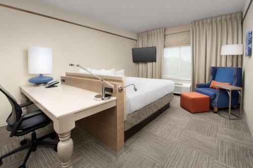 夏洛特夏洛特机场希尔顿花园酒店的酒店客房,配有一张床、一张桌子和椅子