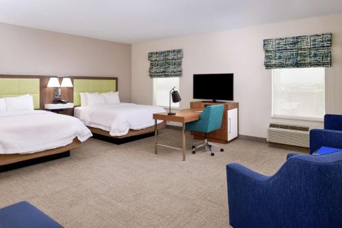 阿兰瑟斯港阿兰萨斯港汉普顿套房酒店的酒店客房设有两张床、一张桌子和一台电视。