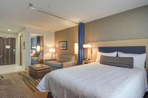 欧文希尔顿Irving/DFW机场北欣庭套房酒店的酒店客房带一张大床和一把椅子