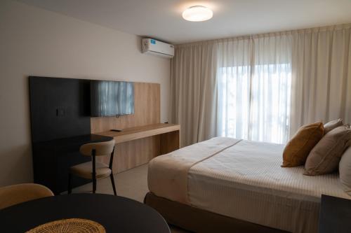 门多萨Urbana Suites的酒店客房配有一张床、一张书桌和一台电视。