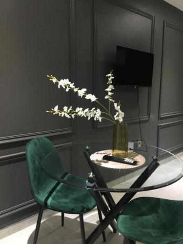 索韦托Black Rose Guesthouse的花瓶和两把绿色椅子的玻璃桌
