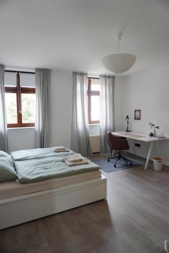 帕塞瓦尔克Wohnen im alten Standesamt的白色卧室配有床和书桌