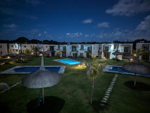 格兰高伯Blissful Abode GV的夜间带两个游泳池和遮阳伞的度假庭院