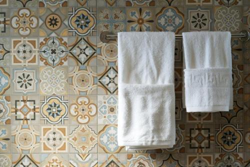 凯法利尼亚岛Villa Lassi Fos的两条白色毛巾挂在墙上,铺着瓷砖