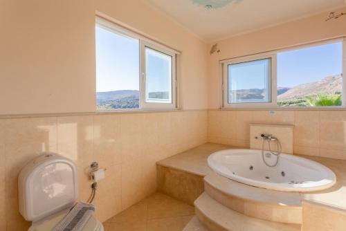 圣特里亚斯Villa Pelagos的带浴缸和卫生间的浴室以及窗户。