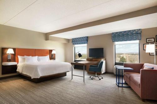 埃夫拉塔埃夫拉塔高山温泉希尔顿恒庭旅馆&套房酒店的酒店客房配有一张床、一张书桌和一张沙发。