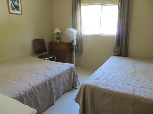 沃萨加比奇海滩林地雪松家庭小屋度假村的一间卧室设有两张床和一个带风扇的窗户。