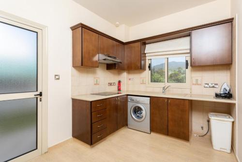 帕福斯Villa Rose的厨房配有木制橱柜和洗衣机。