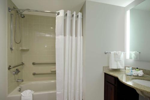 达尼亚滩劳德代尔堡机场邮轮码头希尔顿惠庭套房酒店的浴室配有淋浴帘和盥洗盆。