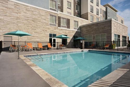 佛罗伦萨Homewood Suites By Hilton Florence的一座带椅子和遮阳伞的游泳池位于一座建筑旁边