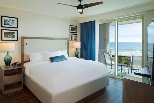 希尔顿黑德岛Hilton Grand Vacations Club Ocean Oak Resort Hilton Head的一间卧室设有一张床和一个海景阳台