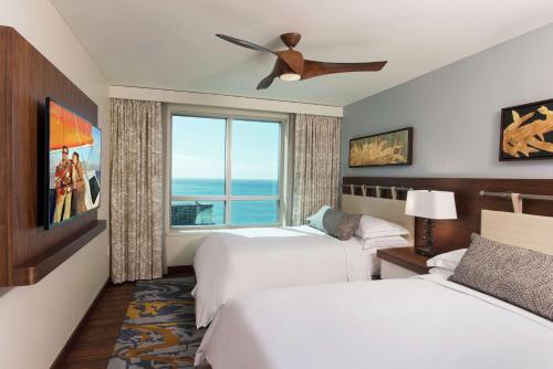 檀香山Hilton Grand Vacation Club The Grand Islander Waikiki Honolulu的酒店客房设有两张床和窗户。