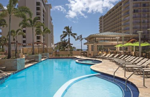 檀香山Embassy Suites by Hilton Waikiki Beach Walk的一个带椅子的大型游泳池和一间酒店