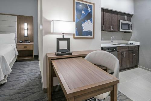 休斯顿Homewood Suites By Hilton Houston Memorial的酒店客房设有一张桌子、一张床和一间厨房。