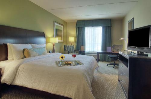 皮尔兰Hilton Garden Inn Houston-Pearland的一间酒店客房,配有一张带鲜花托盘的床