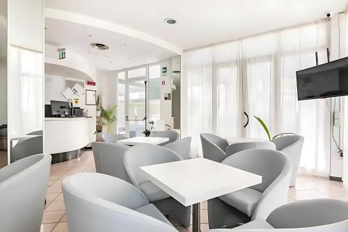 里米尼Hotel Villa Argia Rimini Marina Centro的一间设有白色桌椅的等候室