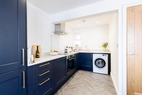 斯托克斯利CRINGLE COTTAGE, The Lanes Cottages, Stokesley的厨房配有蓝色橱柜和洗衣机。