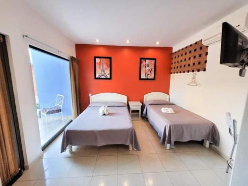 Iguala de la IndependenciaHOTEL OBREGON的一间卧室设有两张床和橙色的墙壁