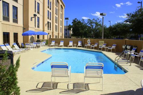 杰克逊维尔杰克逊维尔汉普顿酒店 - I-95中央的一个带椅子和遮阳伞的大型游泳池