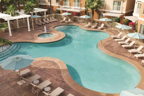 拉昆塔拉坤因塔希尔顿惠庭套房酒店的享有带椅子和遮阳伞的游泳池的上方景色