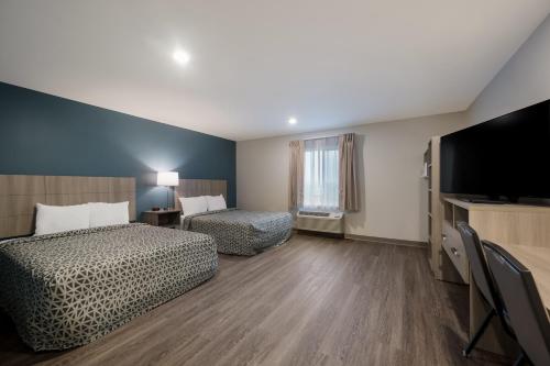 东兰辛WoodSpring Suites East Lansing - University Area的酒店客房设有两张床和一台平面电视。