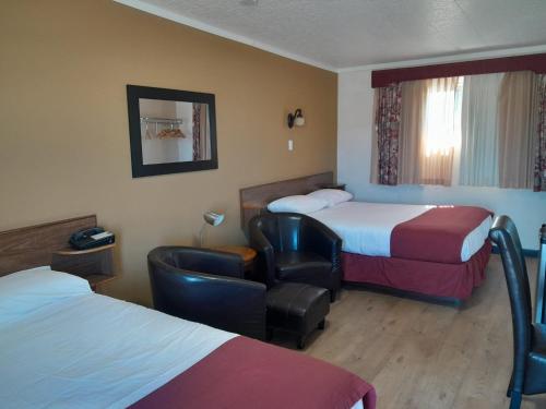 克兰布鲁克Travellers Motel的酒店客房,配有两张床和椅子