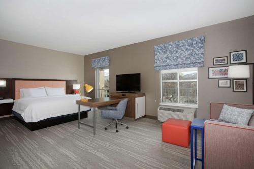 洛根Hampton Inn And Suites Logan, Ut的配有一张床和一张书桌的酒店客房