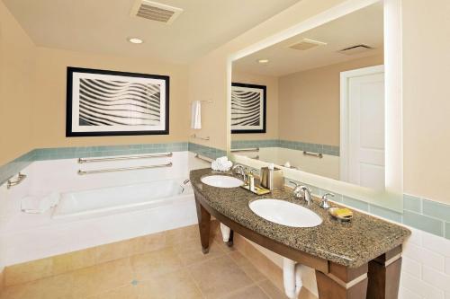奥兰多太阳公园希尔顿分时度假俱乐部的浴室配有2个盥洗盆和1个浴缸。