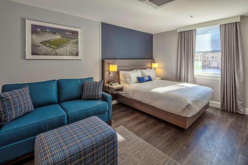州学院Scholar State College, Tapestry Collection by Hilton的酒店客房,配有床和蓝色的沙发