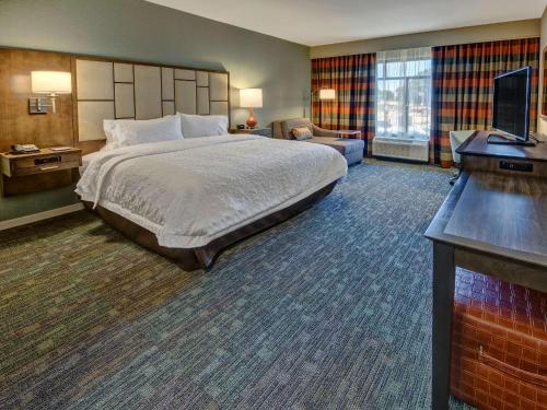 孟菲斯Hampton Inn & Suites Memphis Germantown的配有一张床和一台平面电视的酒店客房