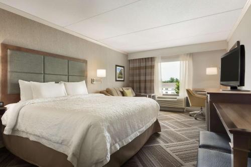 贝德福德Hampton Inn & Suites by Hilton Manchester Bedford的配有一张床和一台平面电视的酒店客房
