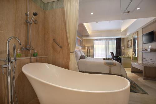 乌布晟诗度假酒店及水疗与会议中心的带浴缸的浴室和1间带1张床的卧室