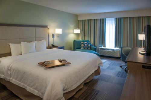 哈拉汉新奥尔良/埃尔姆伍德汉普顿酒店及套房的酒店客房设有一张大床,上面有托盘
