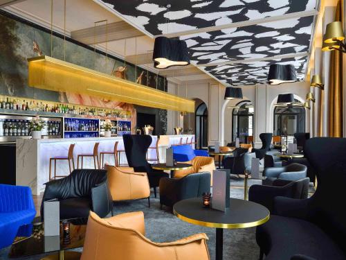 第戎Grand Hotel La Cloche Dijon - MGallery的一间设有蓝色椅子的餐厅和一间酒吧