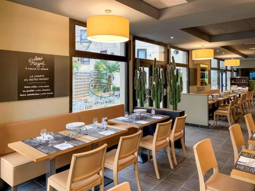 贝桑松ibis Besançon Centre la City的餐厅设有桌椅和大窗户。