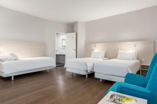 阿姆斯特丹阿姆斯特丹市中心NH酒店的酒店客房,设有两张床和一张蓝色椅子