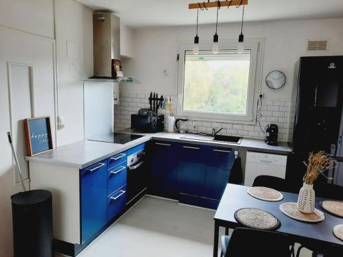 马恩河畔维列Cosy appartement près *RER et Disney, Paris的厨房配有蓝色橱柜、桌子和窗户。