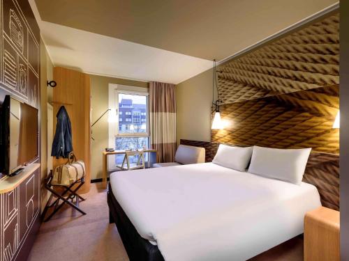 莱比锡莱比锡市宜必思酒店的酒店客房设有一张白色大床和一个窗户。