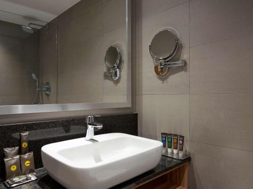 斯丹斯达蒙费雪特伦敦斯坦斯特德机场诺富特酒店的浴室设有白色水槽和镜子