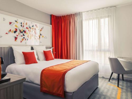 图卢兹美居图卢兹南酒店的一间卧室配有一张大床、红色窗帘和书桌