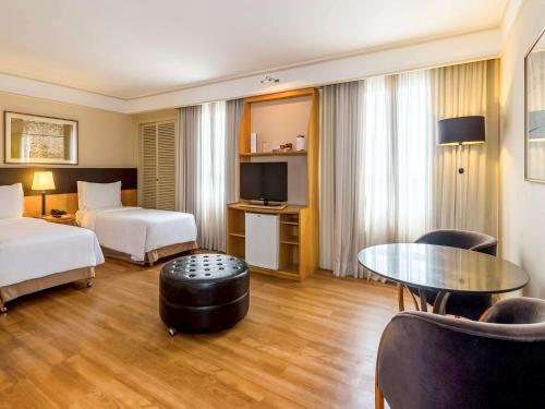 圣保罗Pergamon SP Frei Caneca by Accor的酒店客房设有两张床和一张桌子。