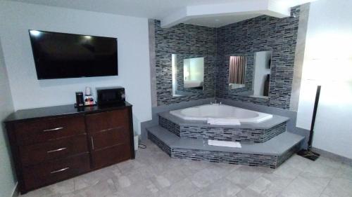 安大略Baymont by Wyndham Ontario的浴室配有大浴缸,墙上配有电视