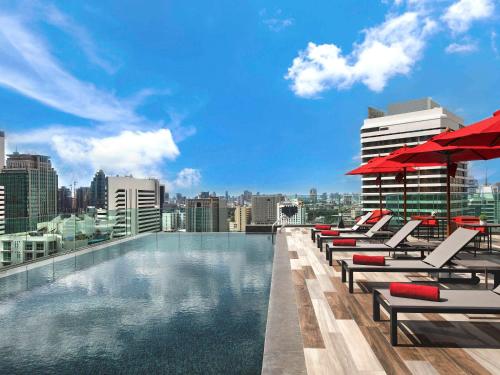 曼谷诺富特曼谷素坤逸4酒店 的一个带躺椅的游泳池,享有城市天际线