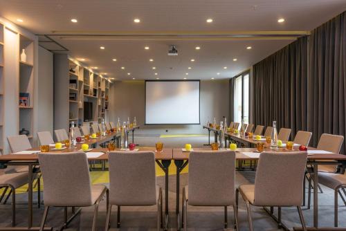 马拉喀什马拉喀什卡雷伊顿丽笙酒店的一间会议室,配有桌椅和屏幕